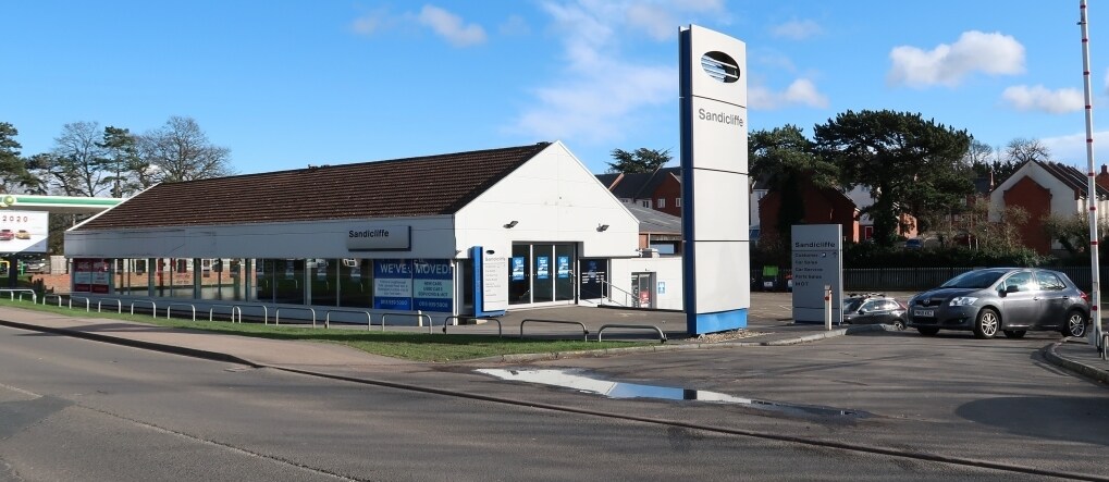An old car dealership with a parked car in front, showcasing a glimpse of its vintage charm.